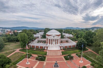 Arial-view-of-a-university-campus-featuring-a-neoclassical-rotunda-surrounded-by-lush-greenery-and-mountains-in-the-background