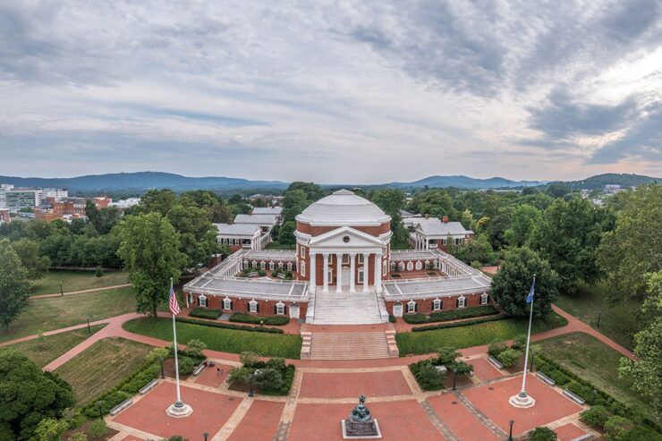 Arial-view-of-a-university-campus-featuring-a-neoclassical-rotunda-surrounded-by-lush-greenery-and-mountains-in-the-background
