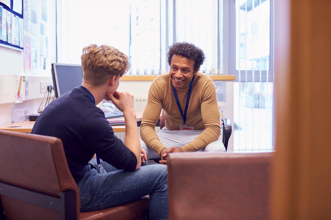 Male college student meeting with campus counselor discussing mental health issues.